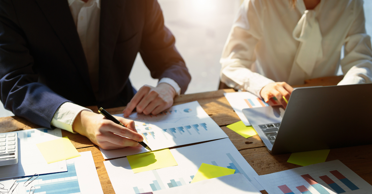 Two people sitting at a table reviewing charts and graphs