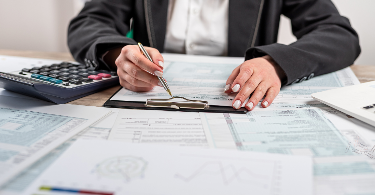 A person sitting at a desk filling out a form on a clipboard.