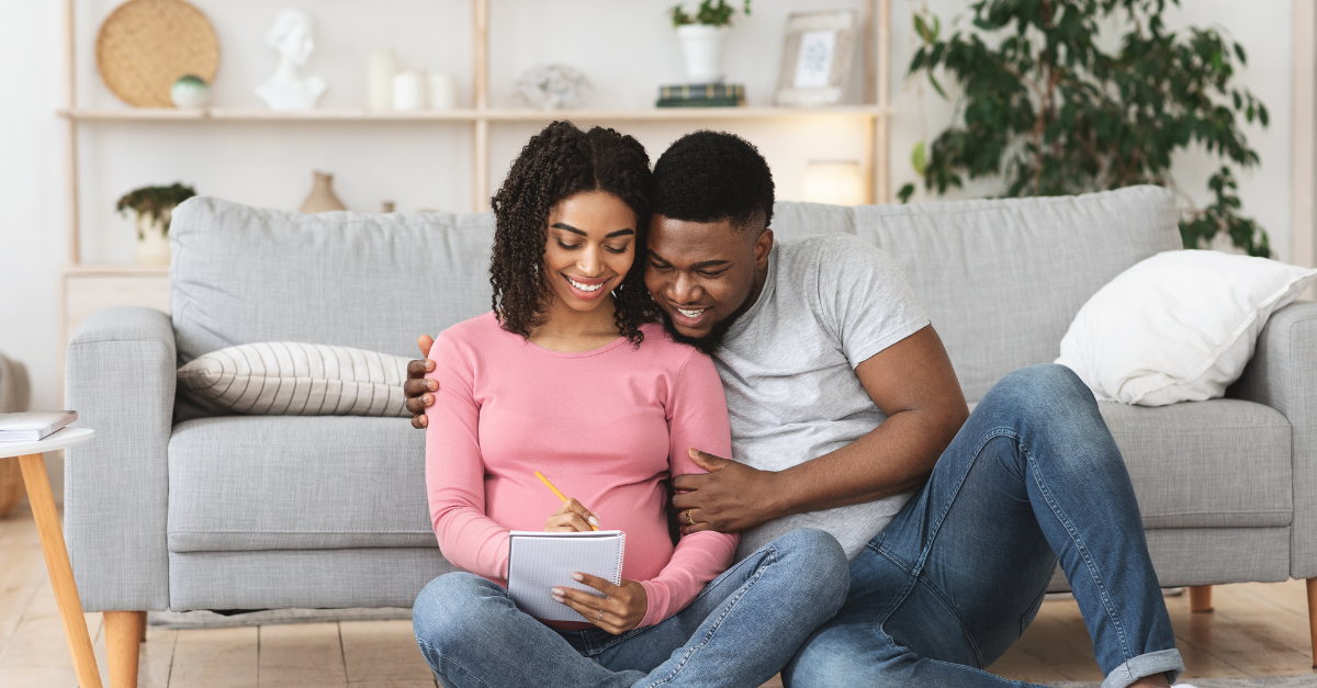 A couple looking at a list sitting in front of a couch