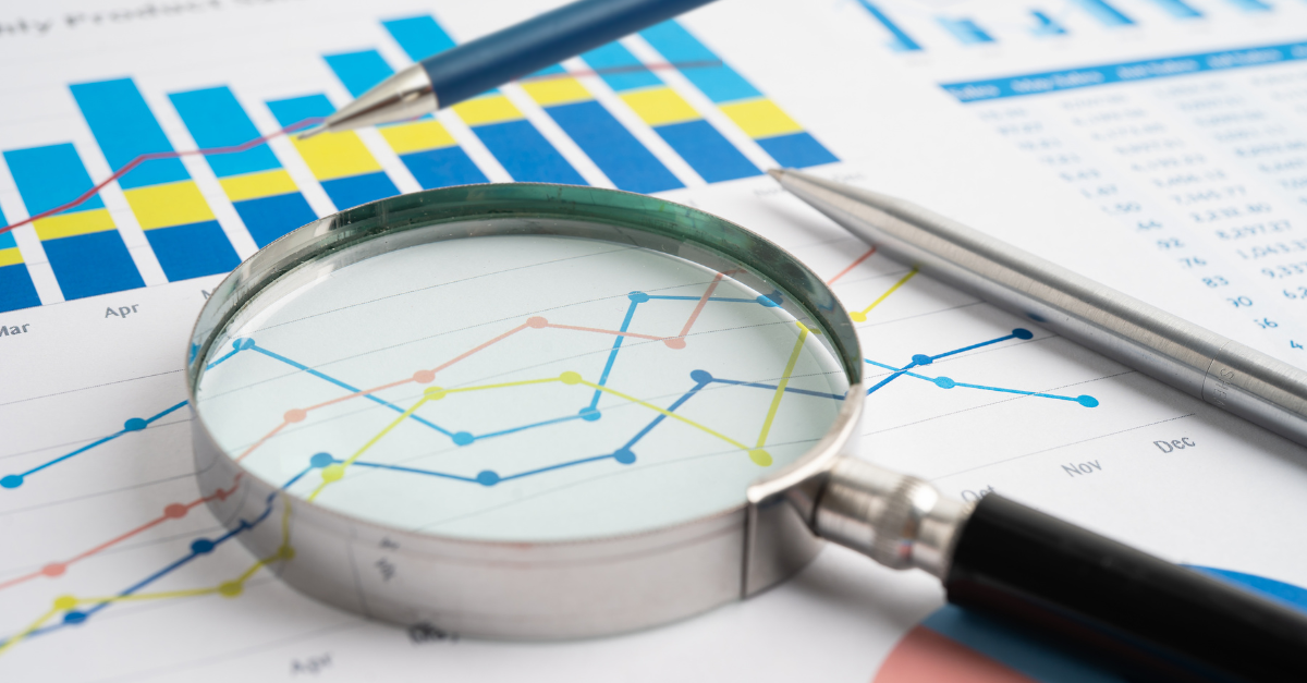 A magnifying glass laying over a line chart.