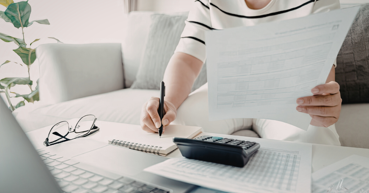 A woman at a desk reviewing documents and taking notes.