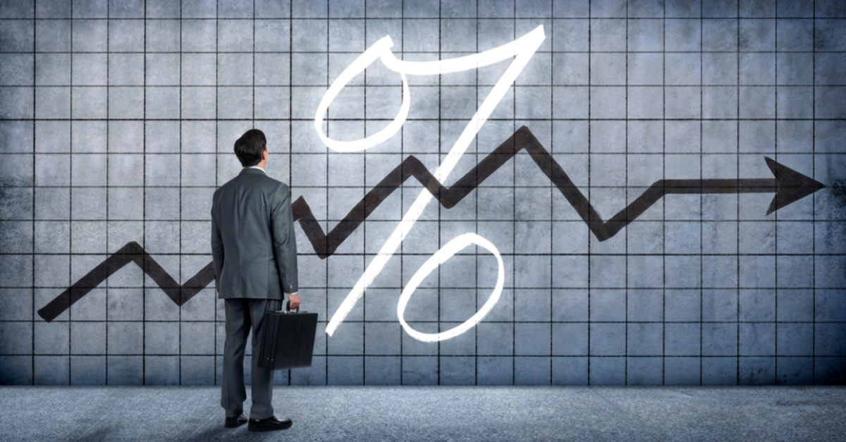 A business man facing a large line graph and percent symbol